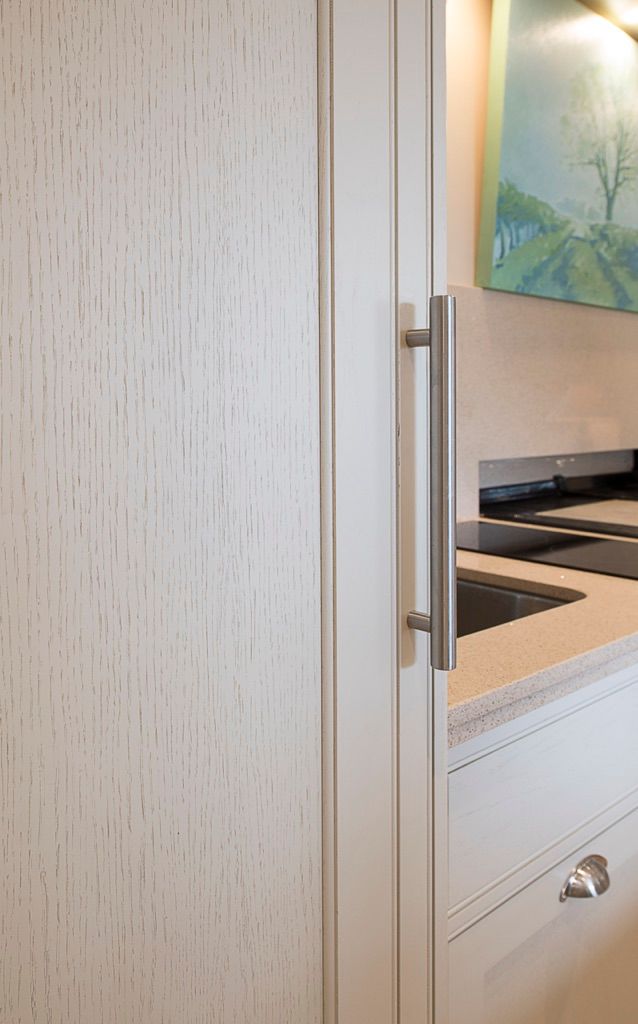 A kitchen with white cabinets , a sink , and a painting on the wall.