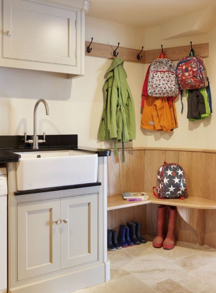A kitchen with a sink and clothes hanging on hooks