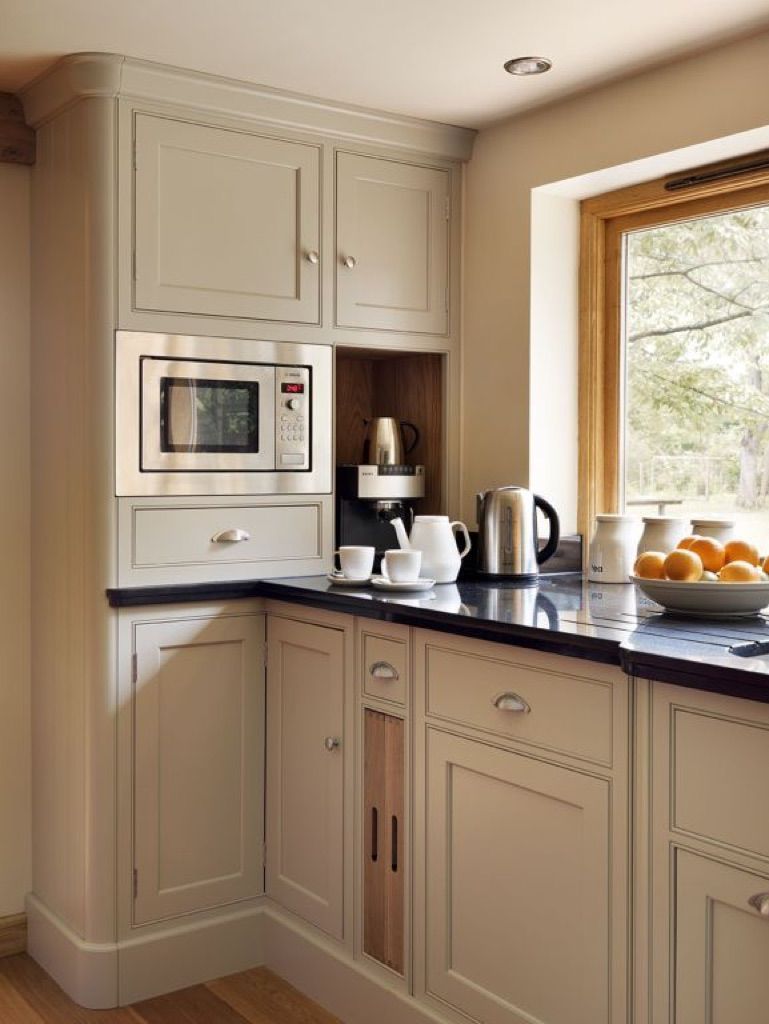 A kitchen with white cabinets , black counter tops , a microwave and a window.