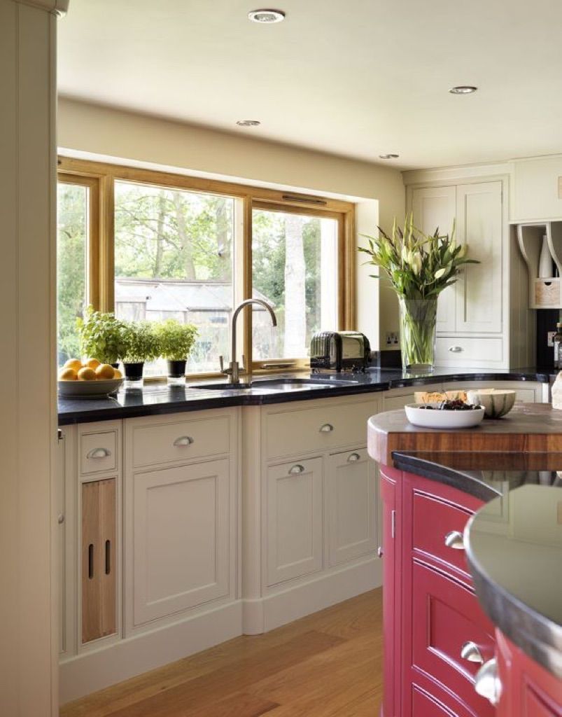 A kitchen with white cabinets and a red island