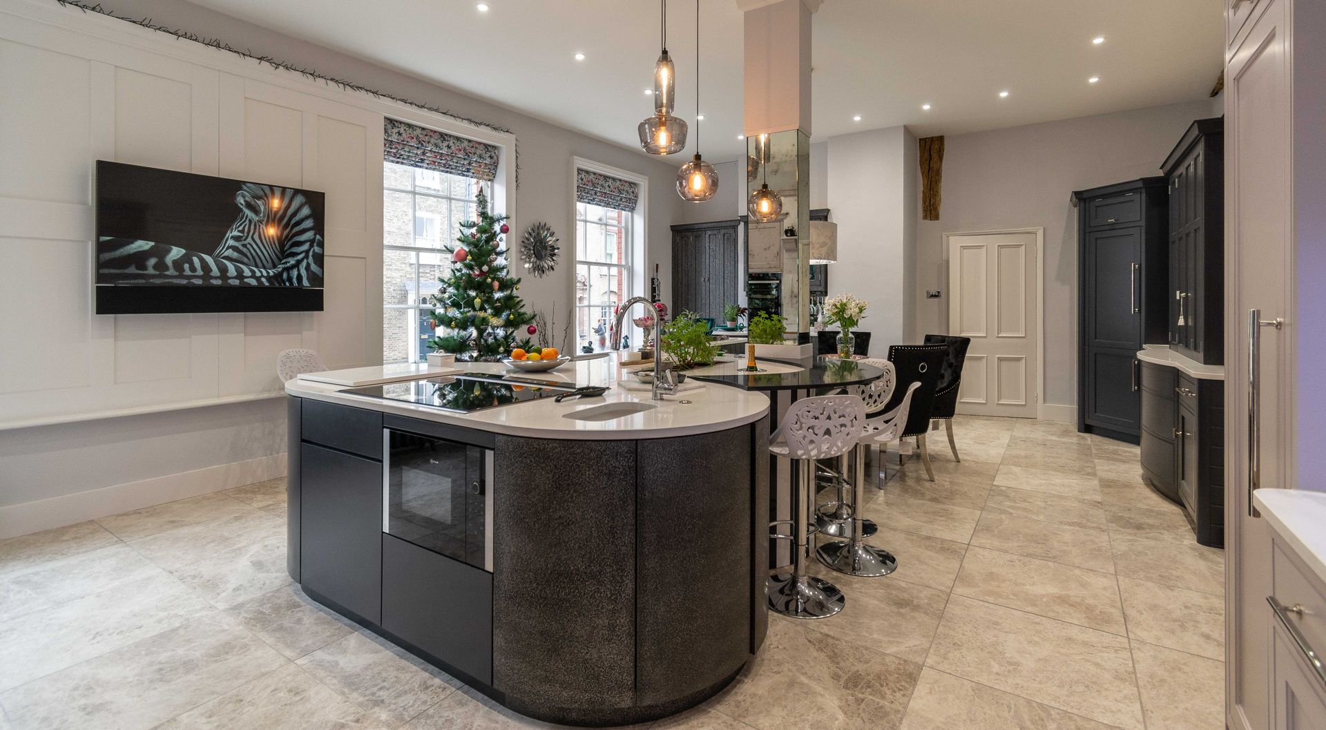 A kitchen with a large island and a christmas tree in the background.
