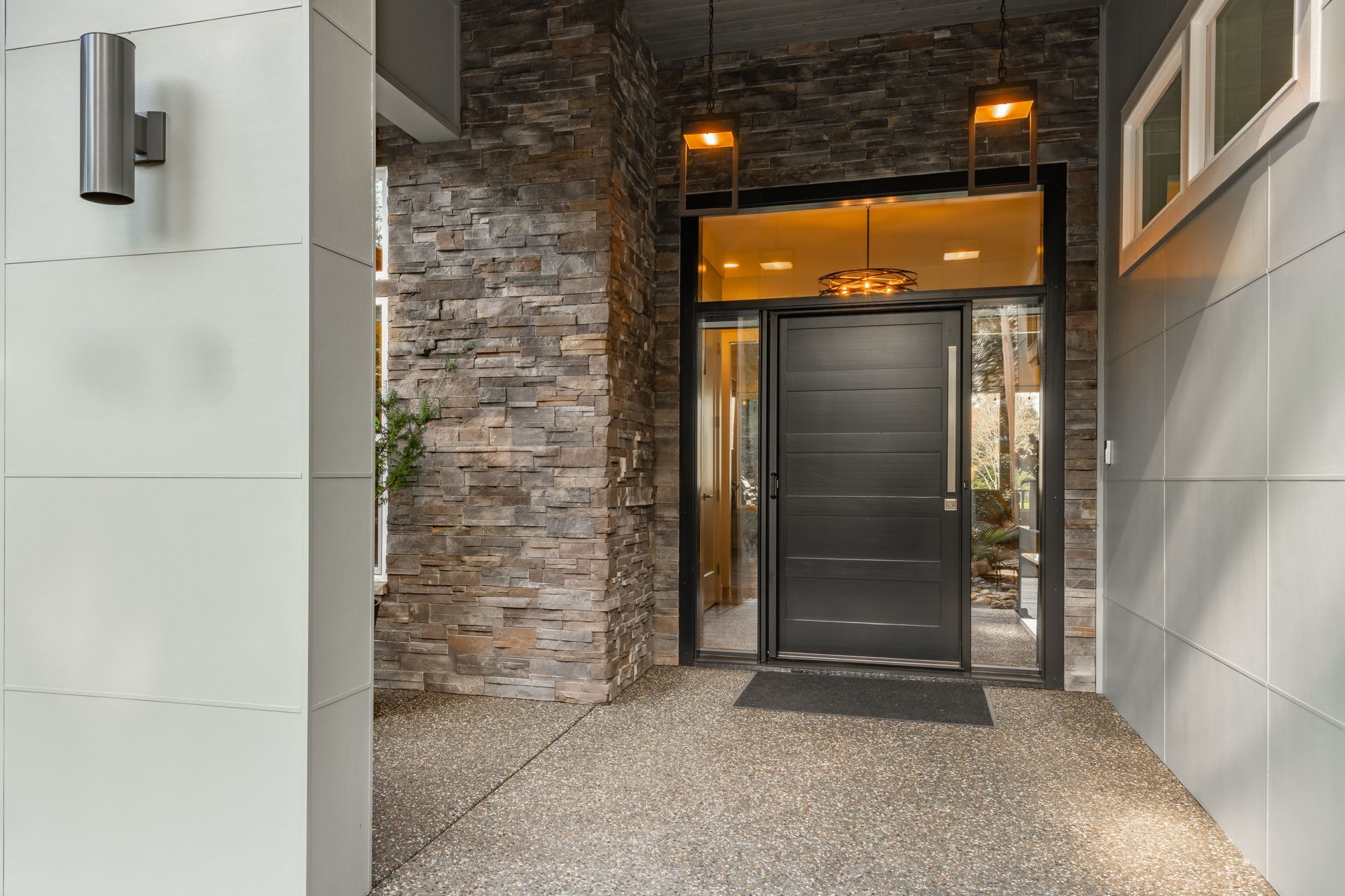 Exterior house entry with dark front door, stone accent wall, and hanging lights.