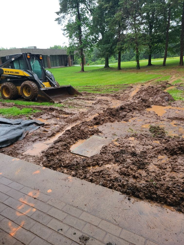 A yellow and black tractor is driving through a muddy field