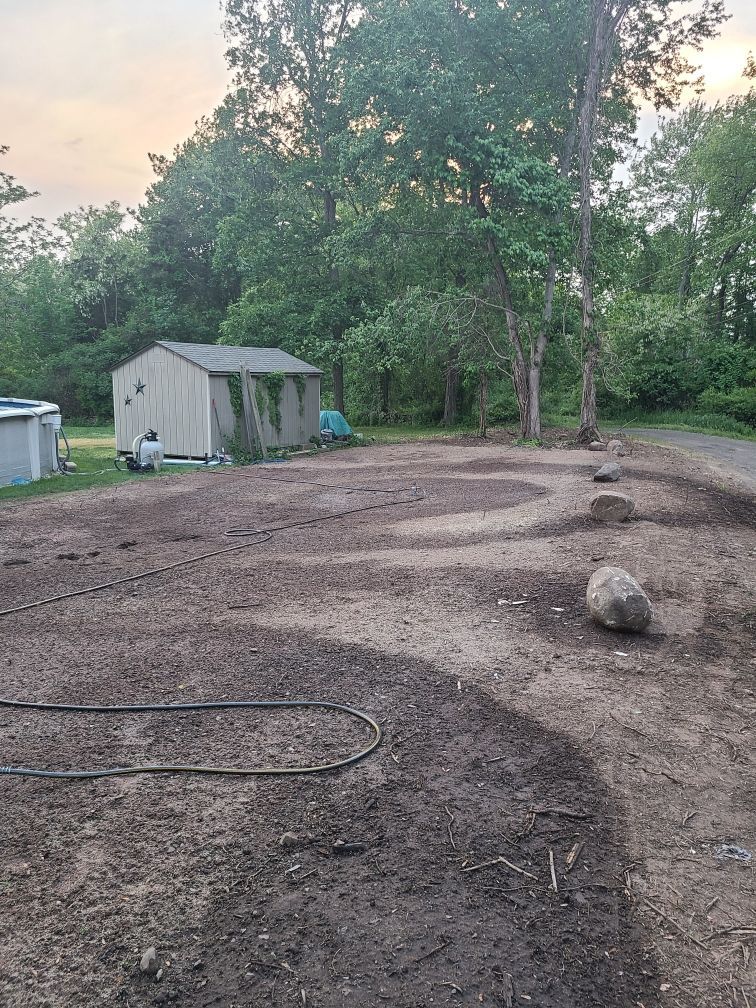 A dirt field with a shed and trees in the background.