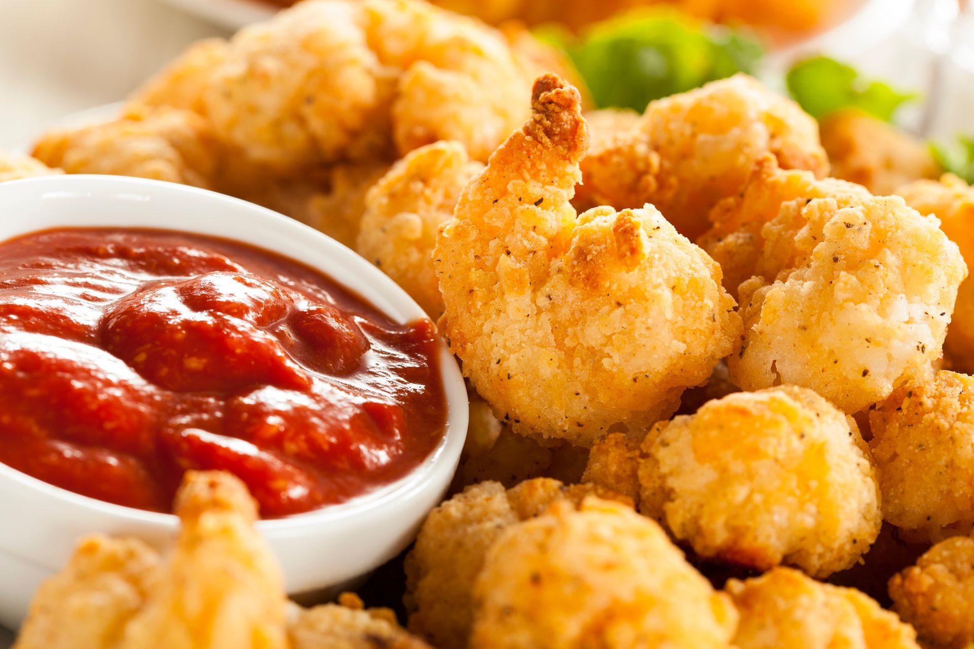 Fried shrimp and popcorn shrimp with a bowl of red dipping sauce.