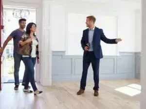 A man in a suit is showing a couple a house.