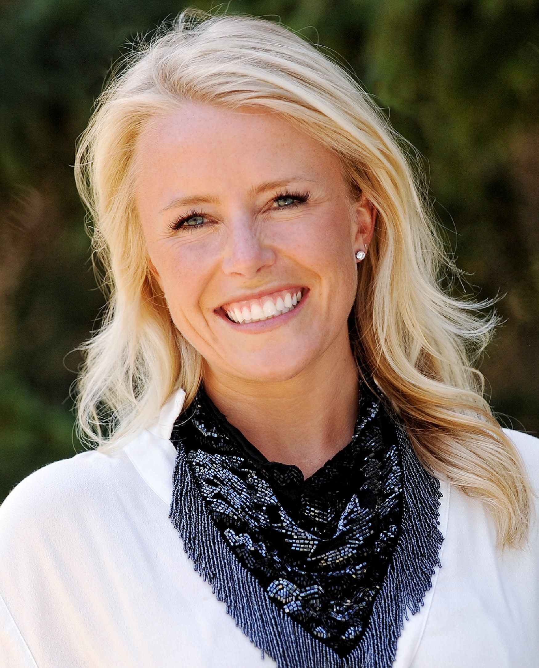 A woman with long blonde hair is smiling for the camera.