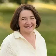 A woman in a white shirt is smiling for the camera.