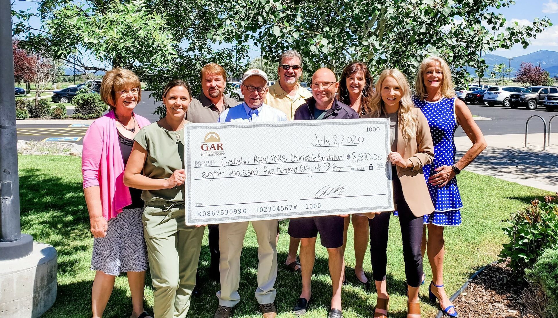 A group of people are standing next to each other holding a large check.