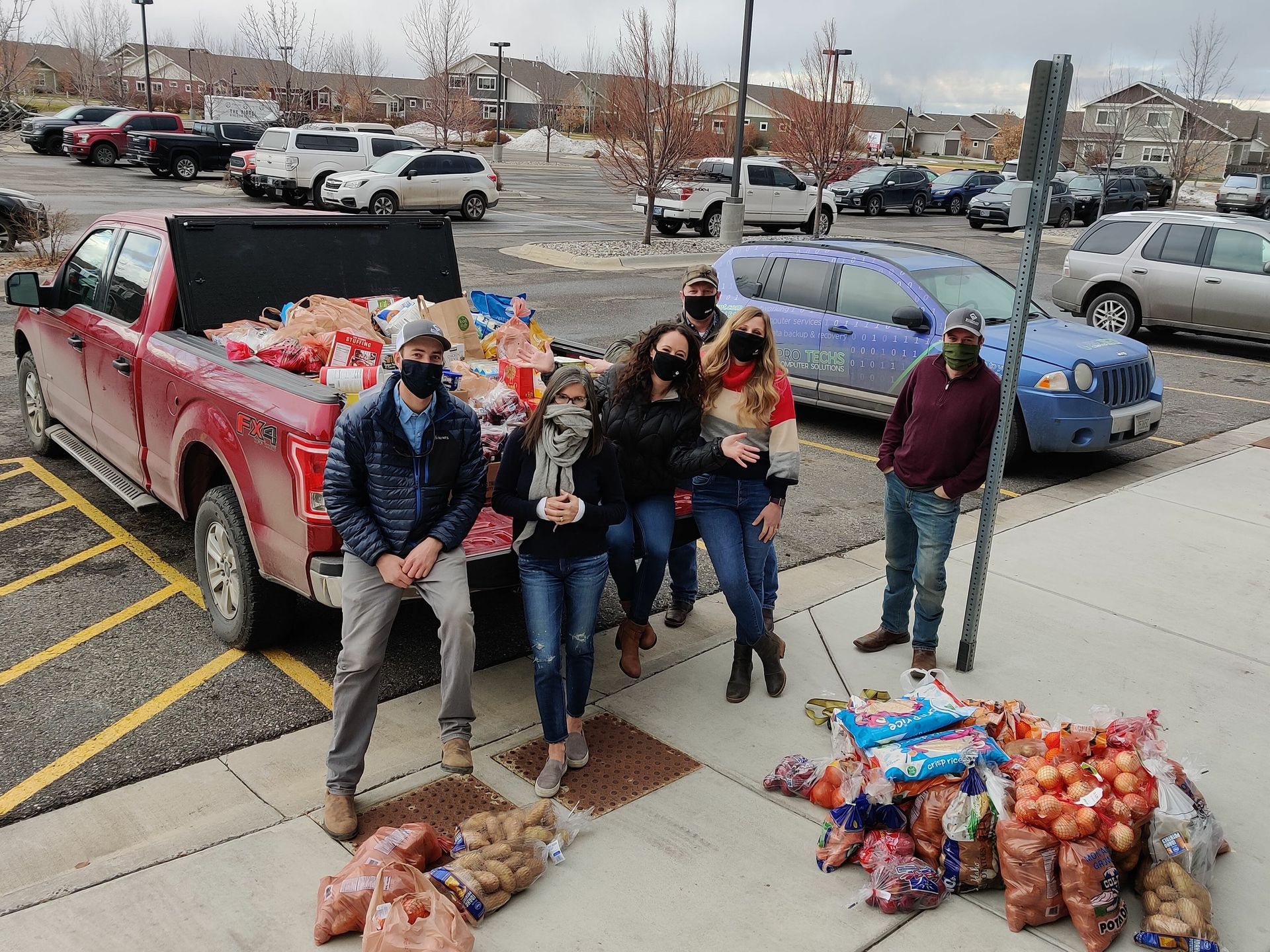 A group of people are standing in front of a truck filled with food.