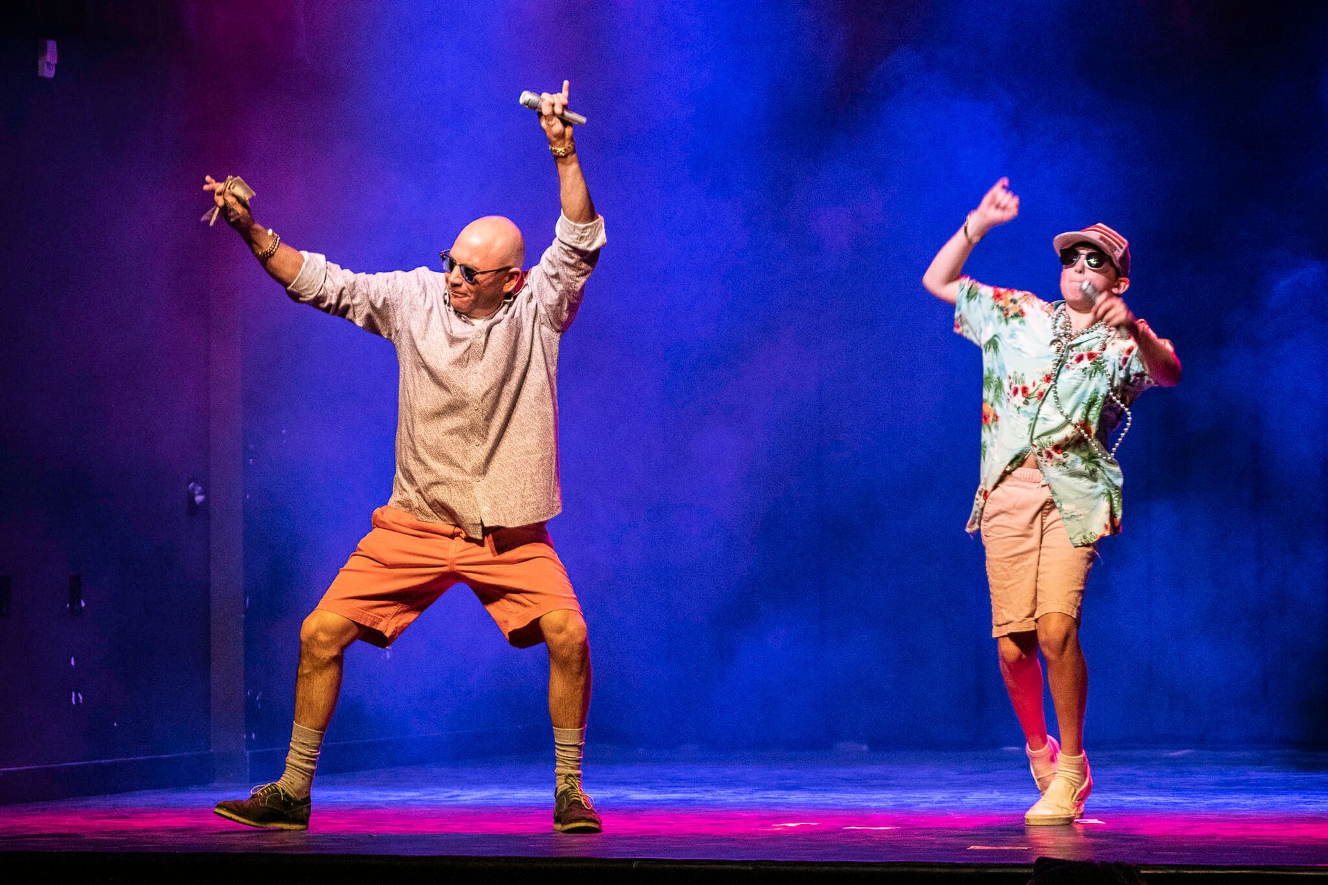 Two men are dancing on a stage in front of a blue light.