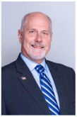 A man in a suit and tie is smiling for the camera.