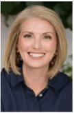 A woman in a blue shirt is smiling for the camera.