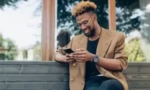 A man is sitting on a bench looking at his cell phone.