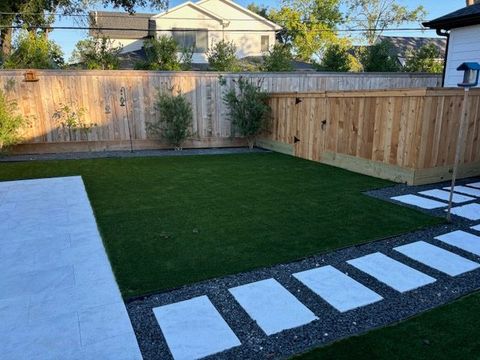 A backyard with a wooden fence and a lush green lawn.