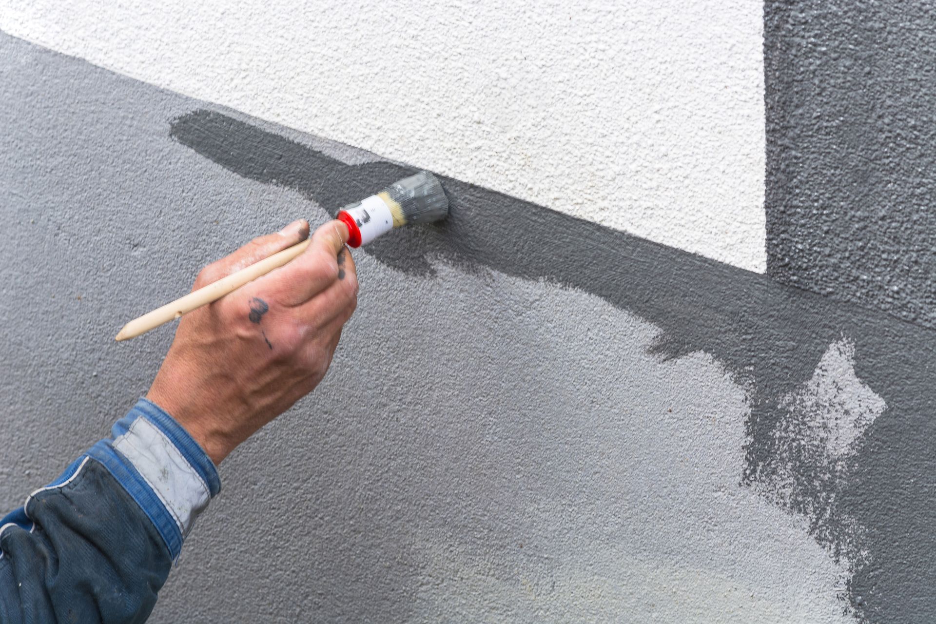 A person is painting a wall with a brush.