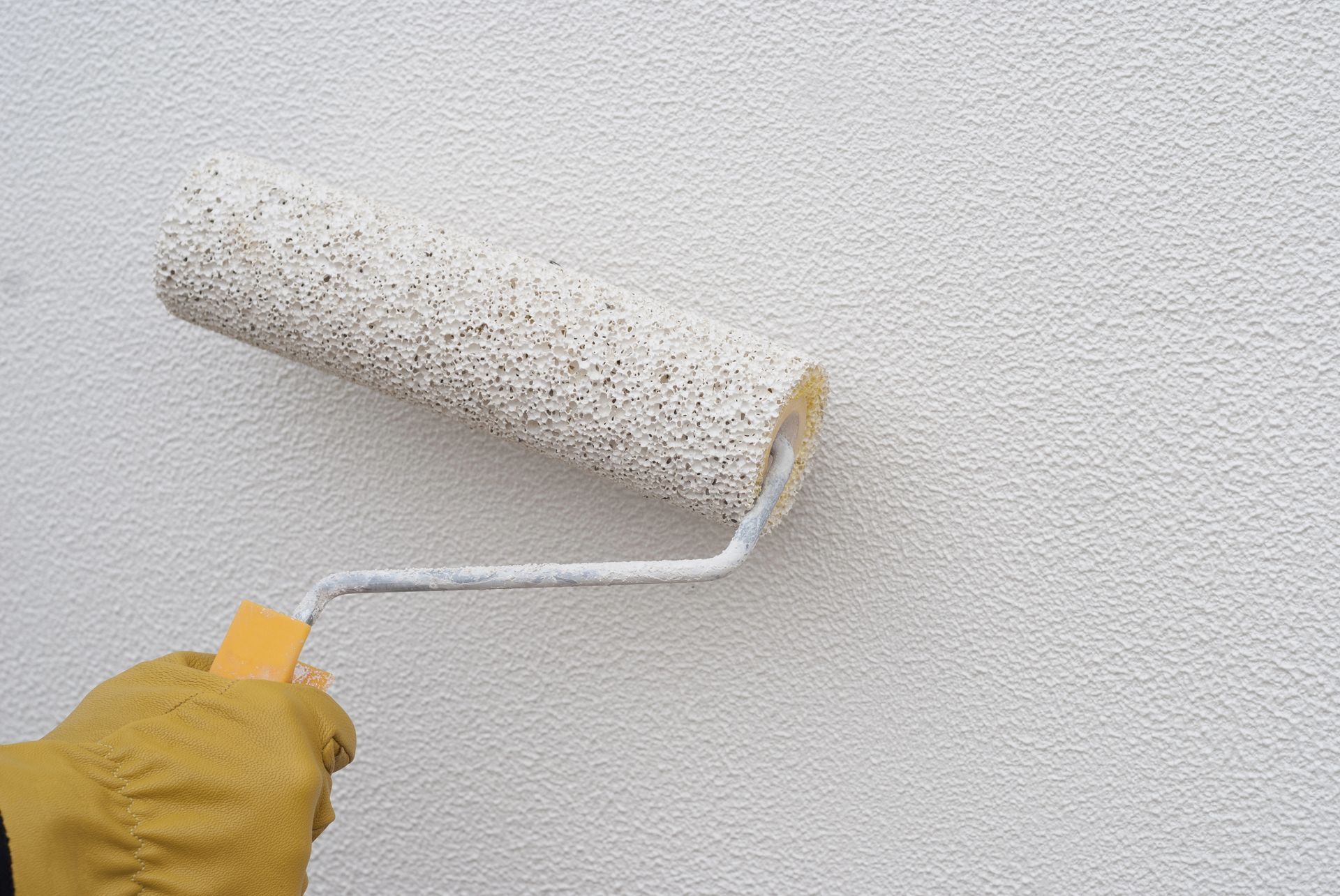 A person is painting a wall with a paint roller.