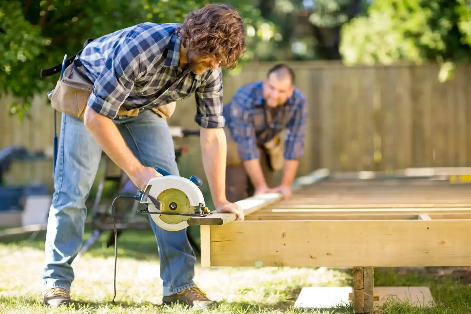 A man is using a circular saw to cut a piece of wood.