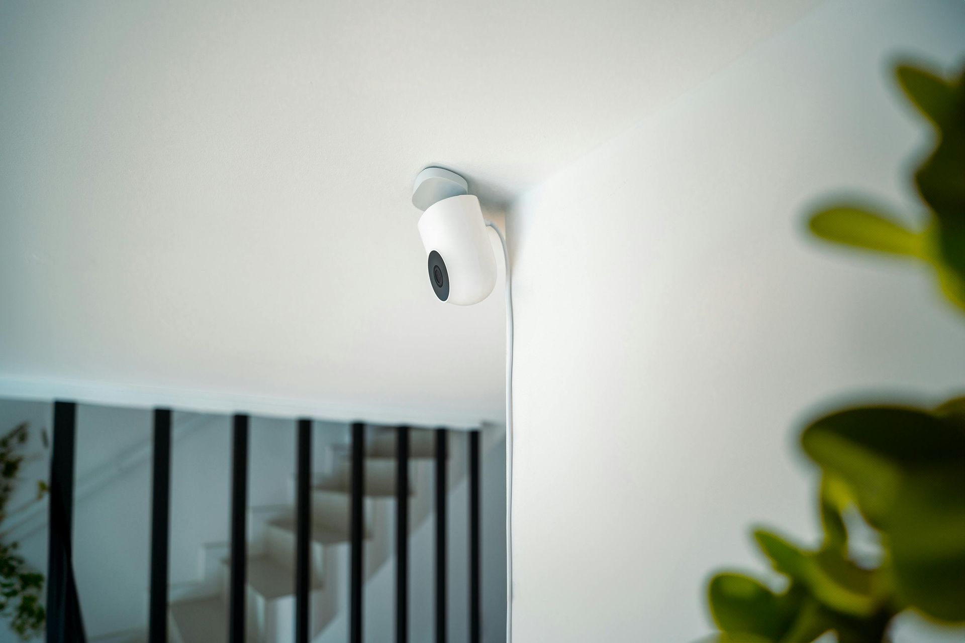 A security camera is mounted on a wall next to a staircase.