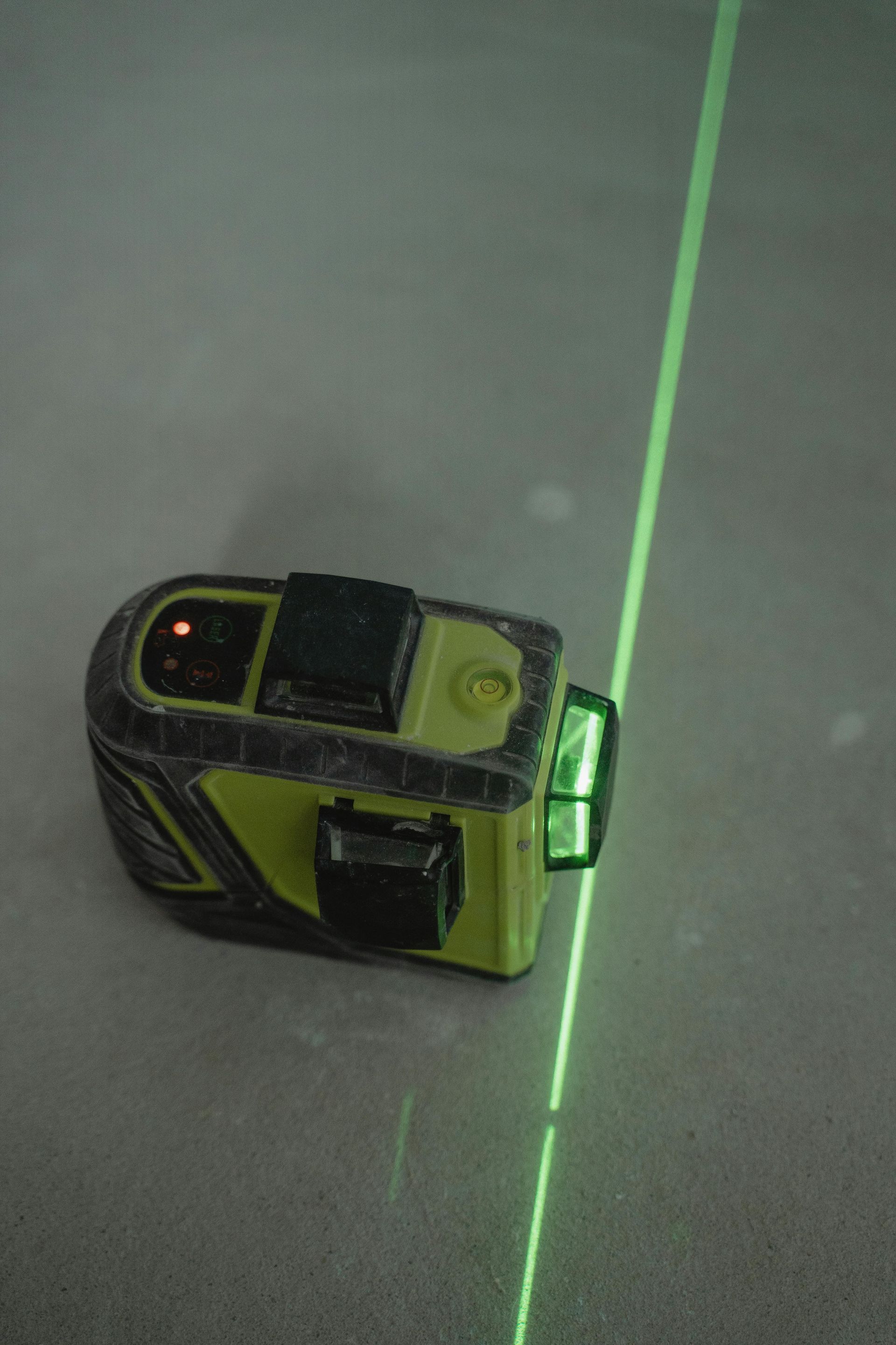 A green laser is sitting on a tiled floor.