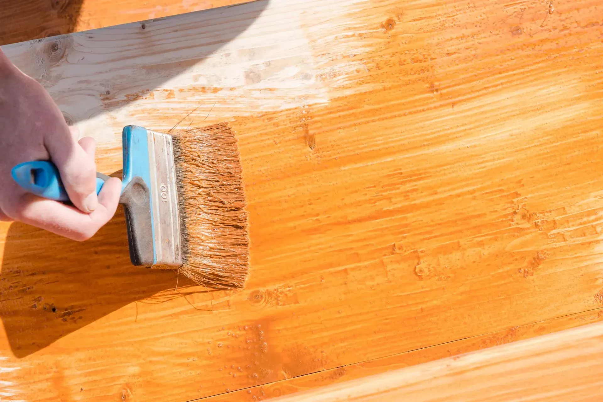 A person is painting a wooden surface with a brush.