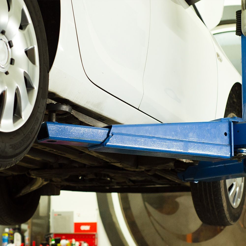 a white car is sitting on a blue lift in a garage