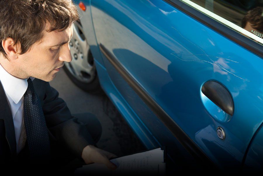 Insurance adjuster examining damage to car exterior