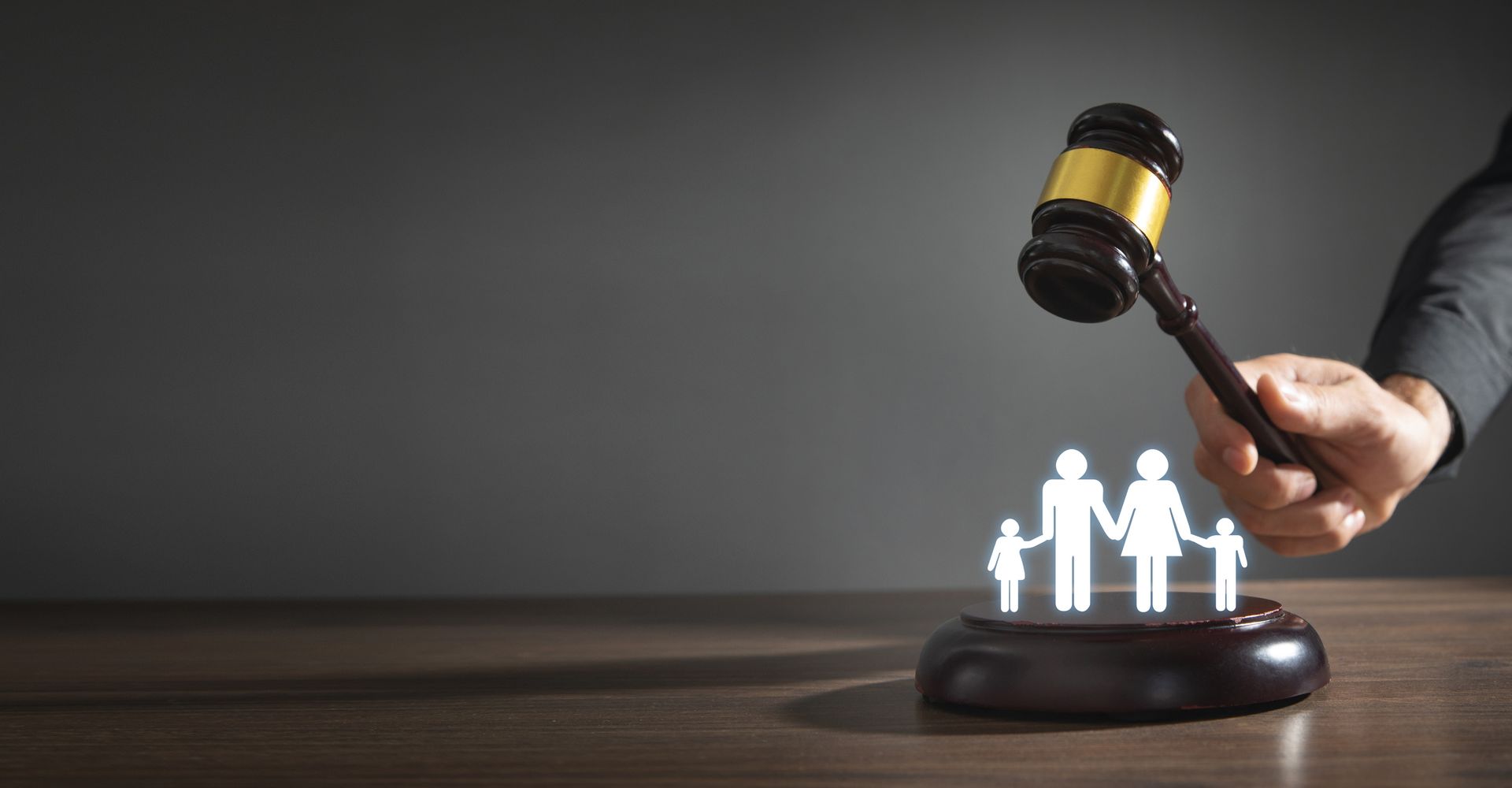 A male hand holding a judge’s gavel with a family symbol. Family law concept. A male hand holding a judge’s gavel with a family symbol. Family law concept.