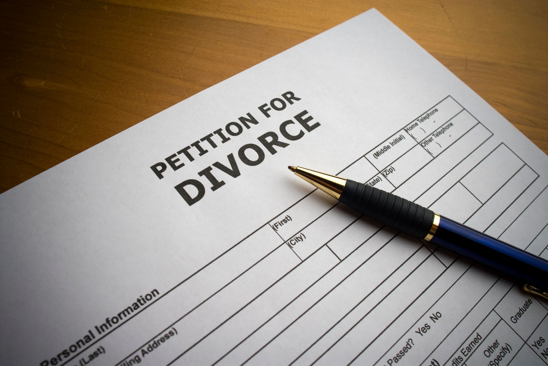 Divorce petition document with pen on wooden surface.