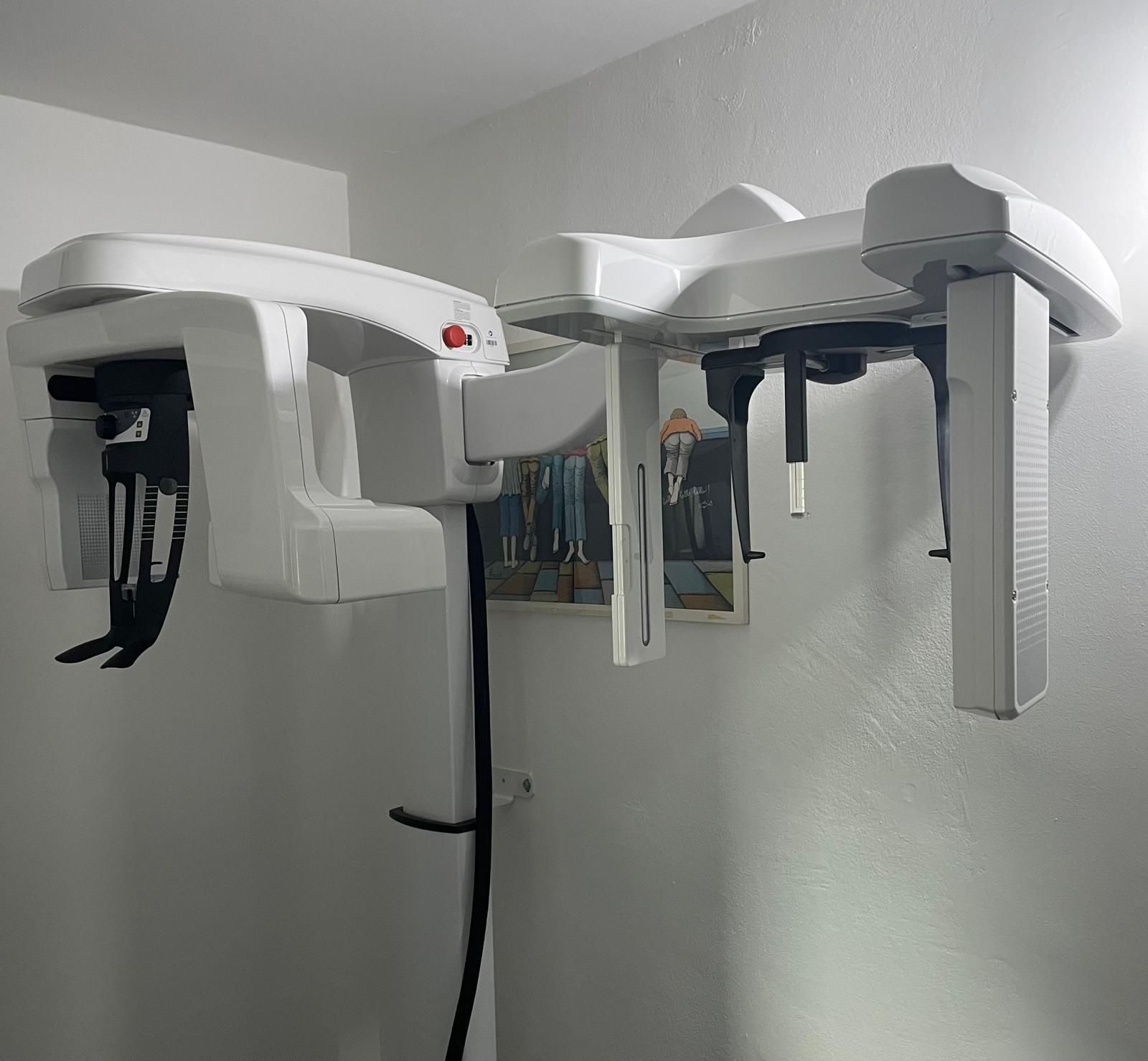 Apparecchio radiografico panoramico dentale bianco montato su una parete di colore chiaro.