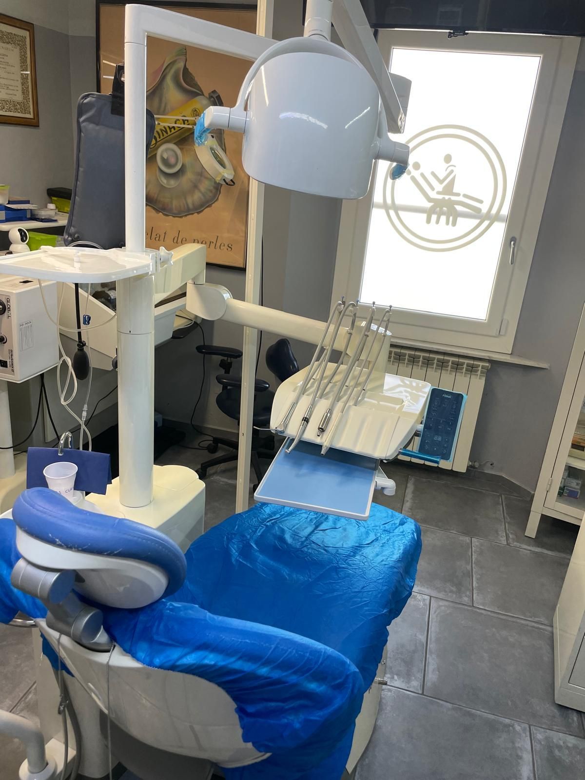 Poltrona odontoiatrica in una clinica, rivestita di blu, con luce e attrezzatura in alto.