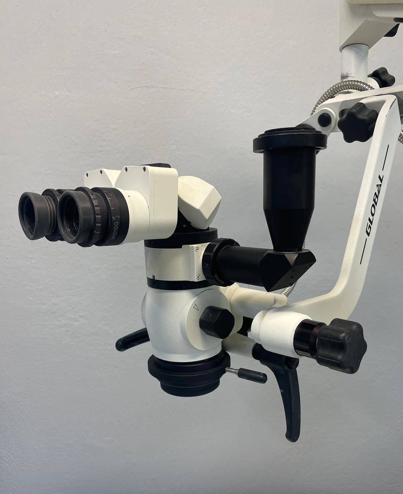 Microscopio chirurgico dentale bianco fissato a una parete, con due oculari e più bracci regolabili.