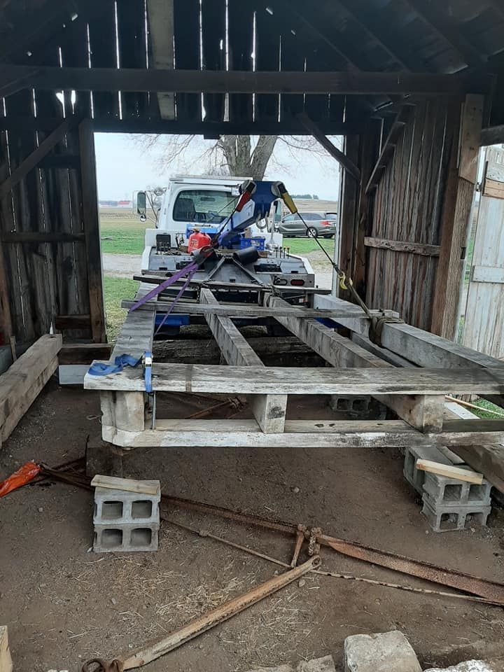A truck is towing a wooden pallet in a barn.