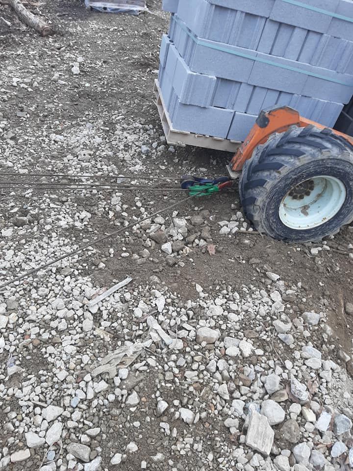A tractor is pulling a trailer full of bricks on a gravel road.