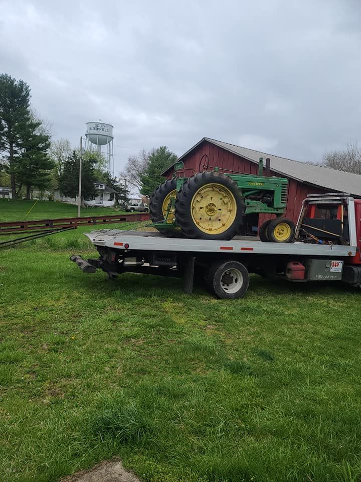 A john deere tractor is being towed by a tow truck.