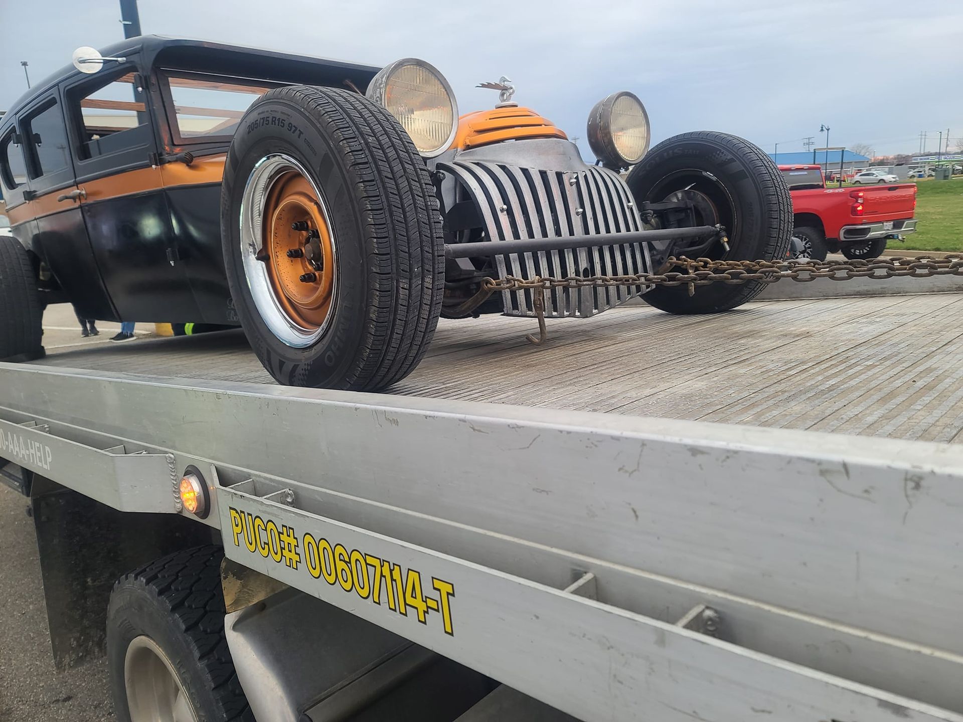 An old car is sitting on top of a tow truck.
