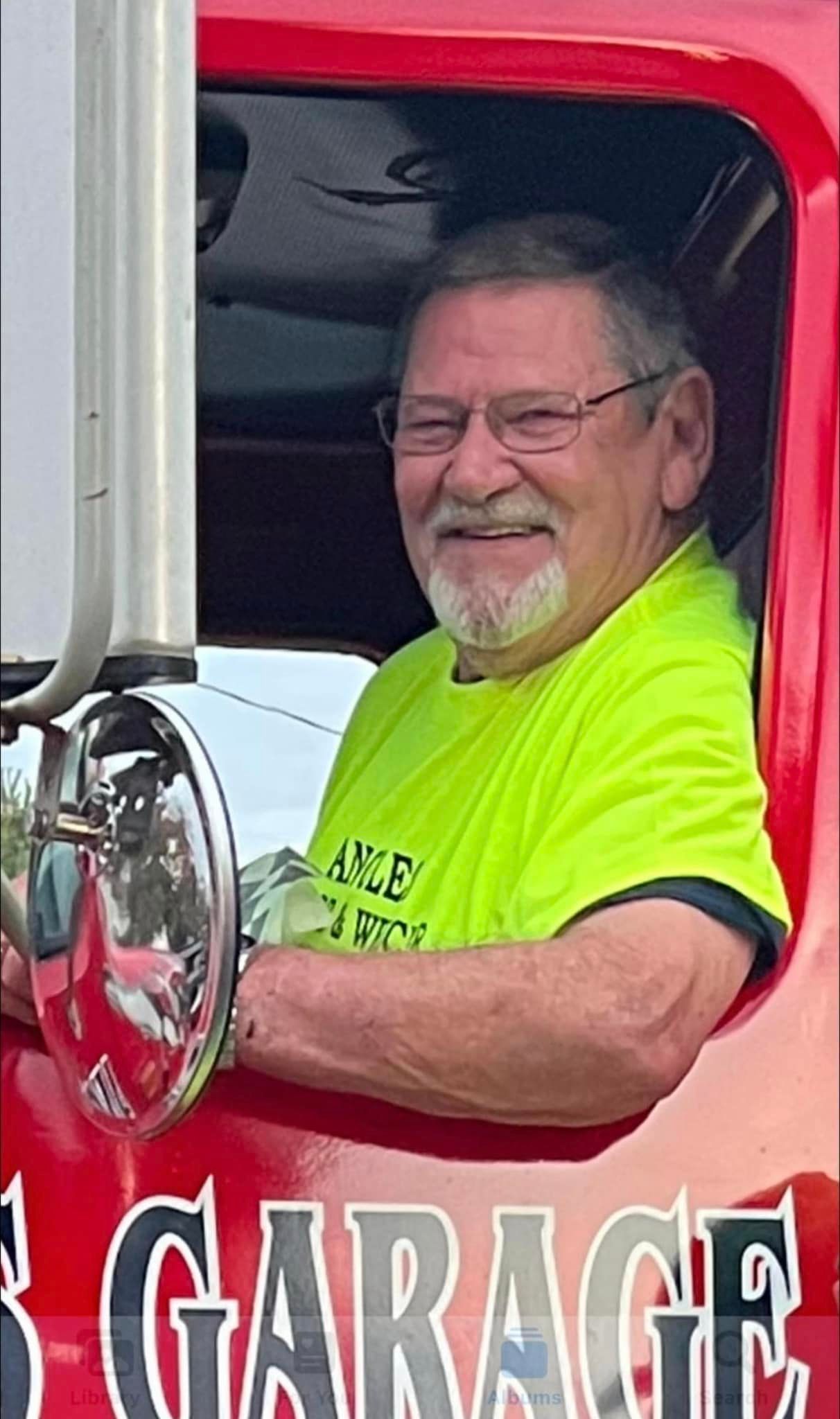 A man in a yellow shirt is driving a red truck.
