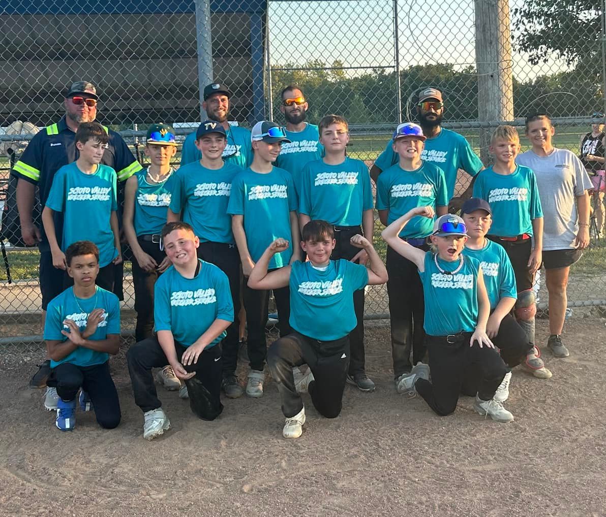 A group of young boys are posing for a picture on a baseball field.