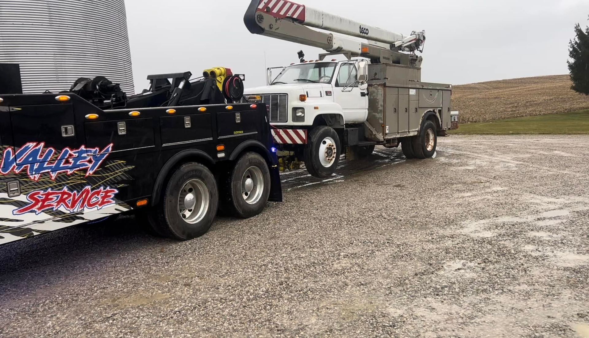 A valley service tow truck is parked in a gravel lot.