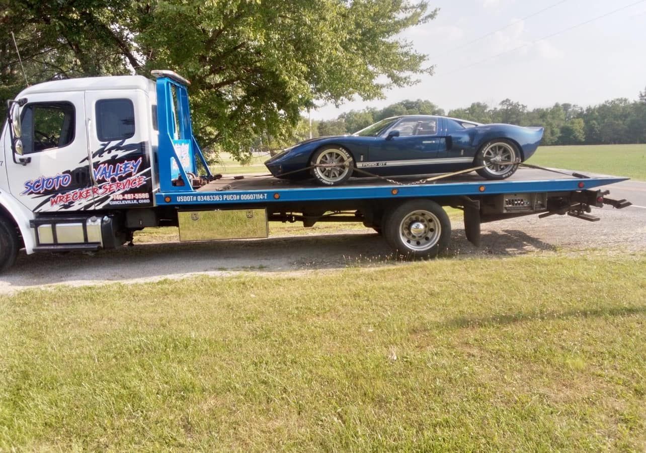 A blue car is on the back of a tow truck.