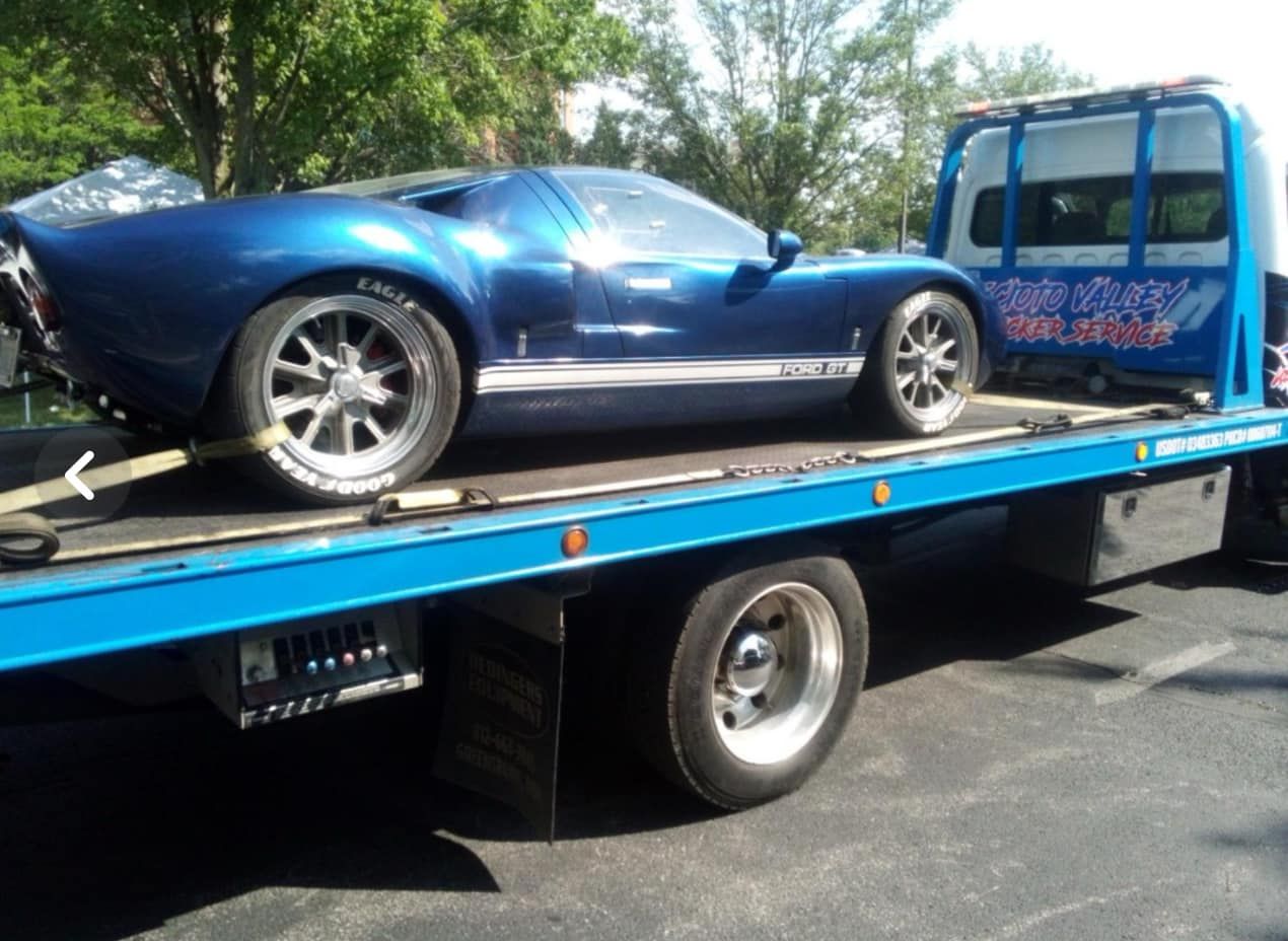 A blue car is being towed by a tow truck