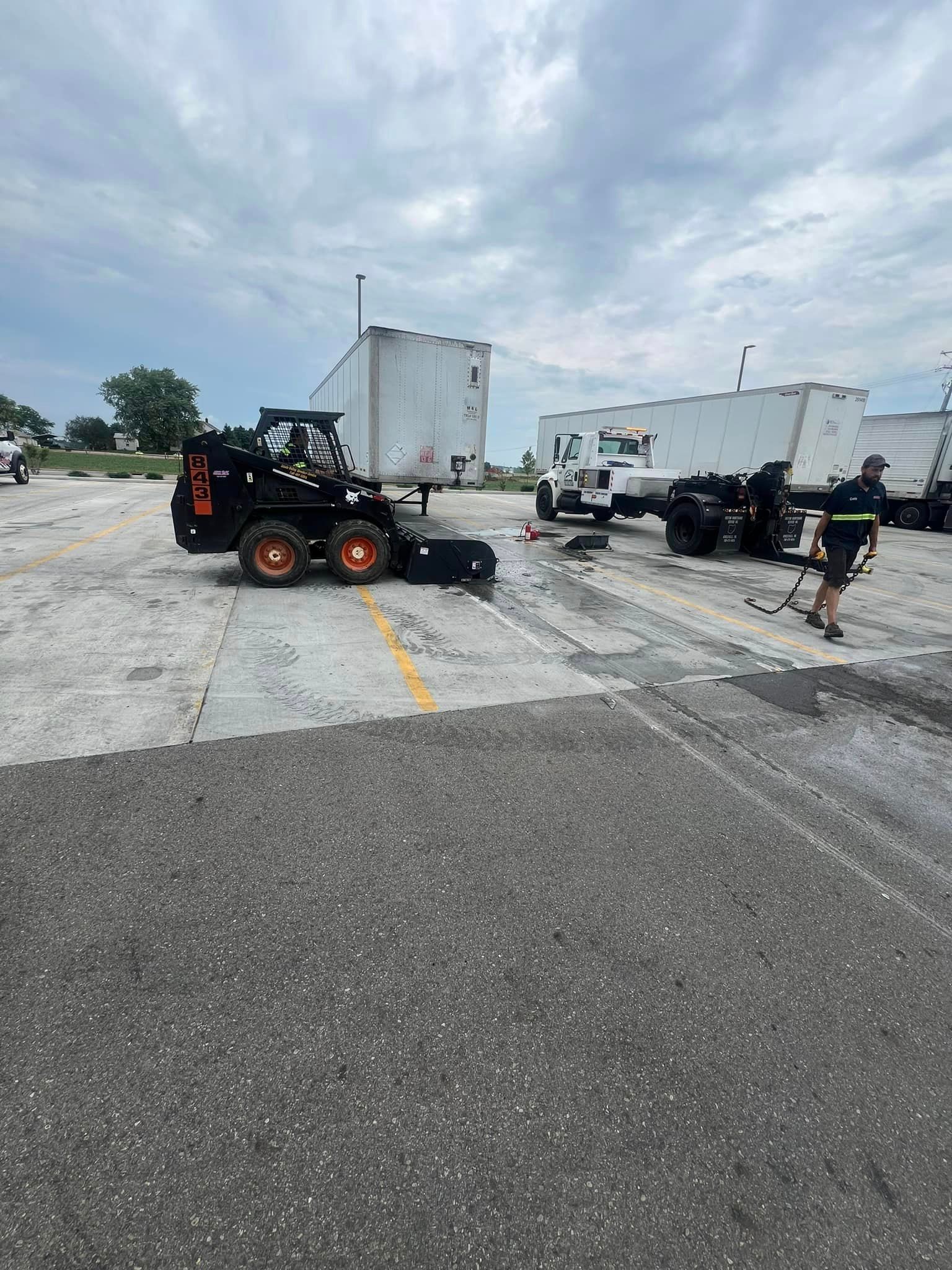 A man is standing next to a bulldozer in a parking lot.