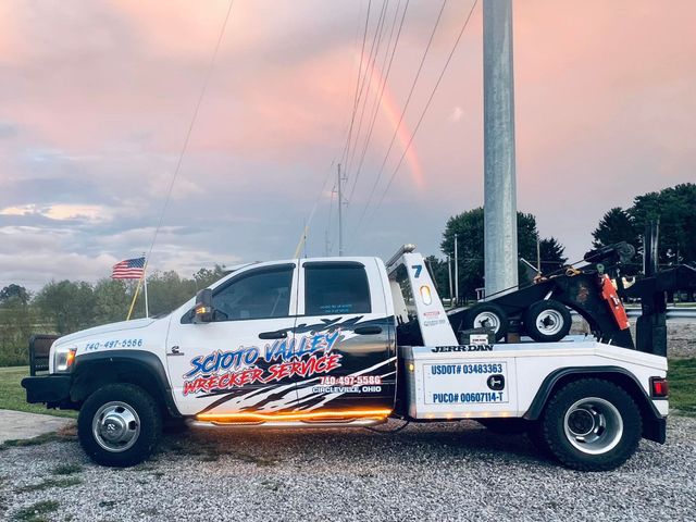 A white tow truck is parked next to a power pole.