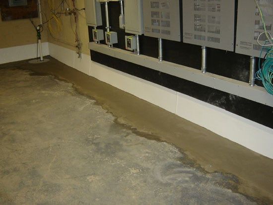 Basement utility room with a concrete floor and exposed pipes and electrical panels along the wall.