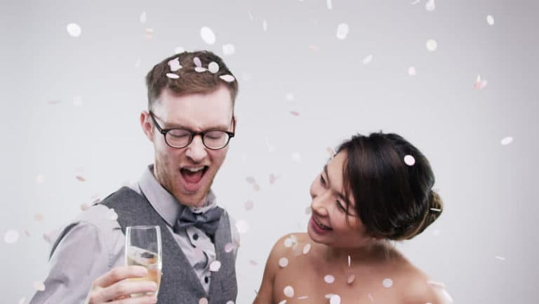 A bride and groom are celebrating their wedding with confetti falling around them.