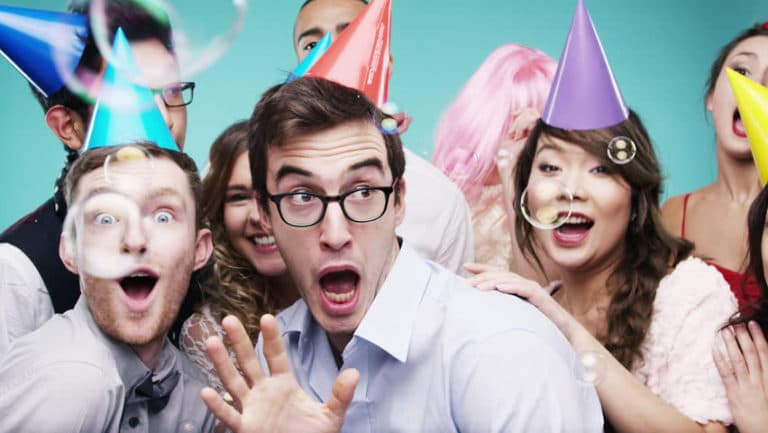 A group of people are wearing party hats and blowing bubbles at a party.