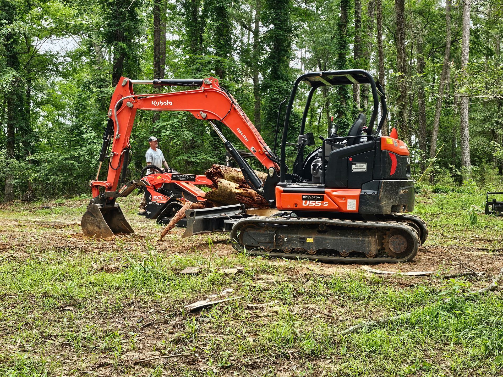 A red and black excavator is sitting in the middle of a field.
