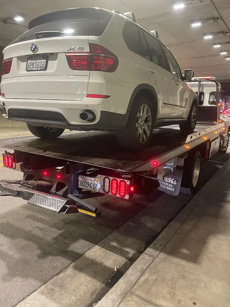 A black SUV being towed on a flatbed tow truck on a highway.