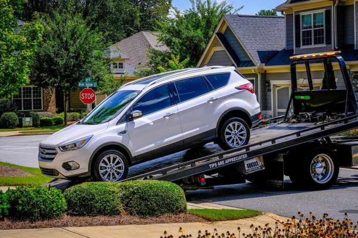 White SUV being towed by a tow truck on a residential street.