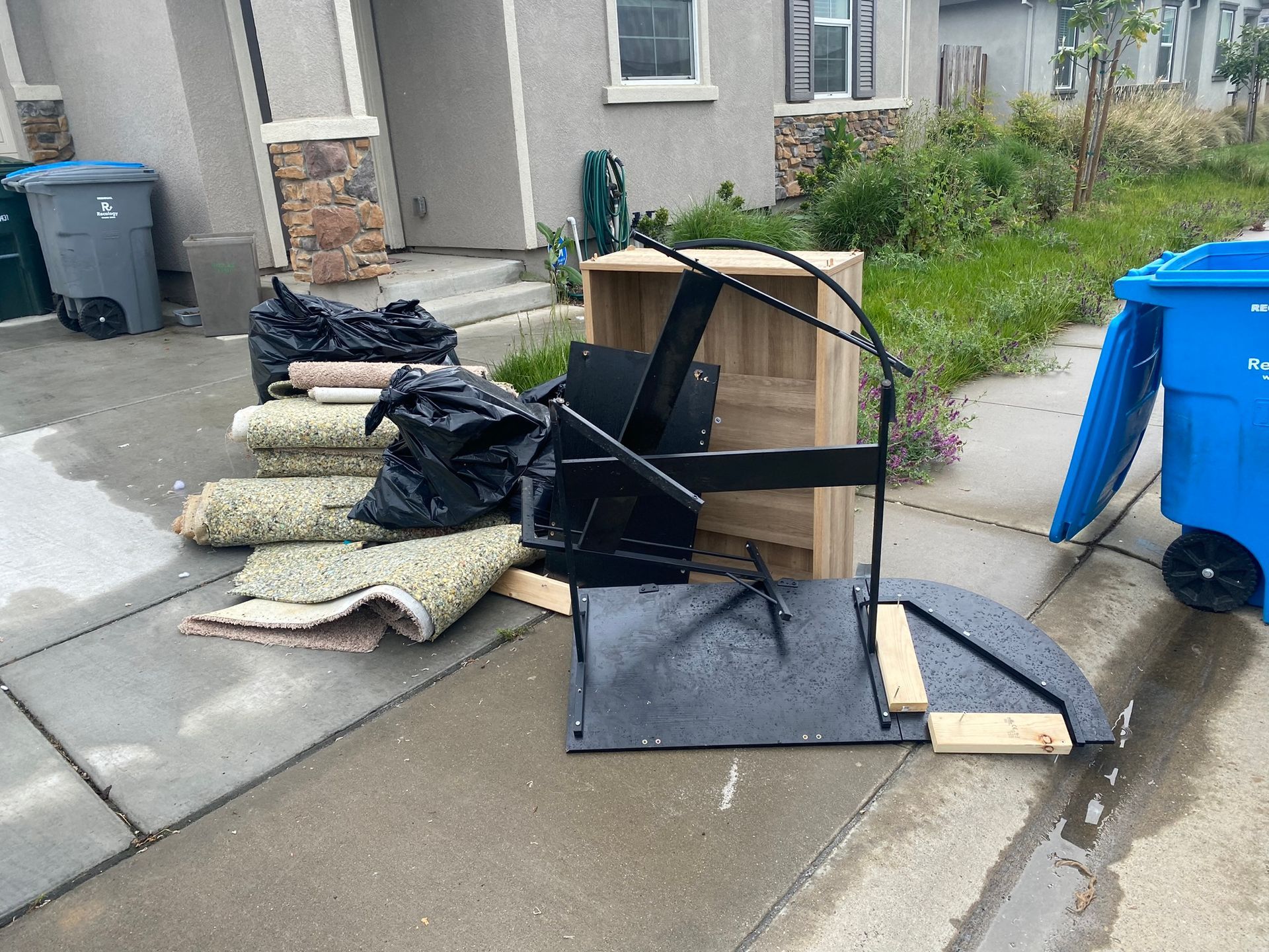 A pile of trash is on the sidewalk in front of a house.